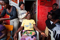 Kenyan women having hair braided, Kisumu region, Kenya, December 2013.