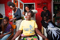 Kenyan women having hair braided, Kisumu region, Kenya, December 2013.