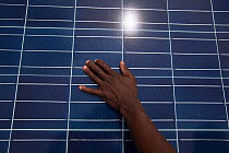 Solar technician's hand rest on solar panel, Rwanda, April 2014.