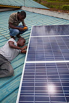 Solar energy technicians checking panel installation, Rwanda, April 2014.