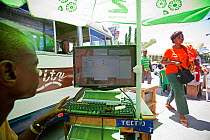 Street stall under a parasol with a desktop computer selling MP3 music downloads, Kariakoo, Dar es Salaam, Tanzania. November 2012.