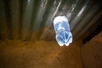 Water filled bottle fixed into a tin roof, dispersing sunlight and acting as a natural lightbulb. Kenya. April 2013.