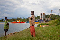 Two children standing in front of Kivuwatt biogas plant under construction. The plant will remove methane from the waters of Lake Kivu and power three genrators to produce 26MW of electricity. Kibuye,...