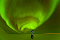 Photographer in front of Northern lights / Aurora borealis glowing brightly over the frozen eastern Beaufort Sea, Arctic National Wildlife Refuge, Alaska Model released.