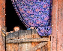 Young girl looking out of a doorway, Paro River Valley. Bhutan, October 2014.