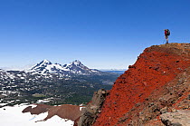 Hiker on the crater rim of Broken Top, and view towards Middle and North Sister. Three Sisters Wilderness, Deschutes National Forest.  Oregon, USA, July 2014.  Model released.