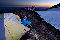 Woman camping on the crater rim of South Sister, Three Sisters Wilderness, Deschutes National Forest.  Oregon, USA, July 2014. Model released.