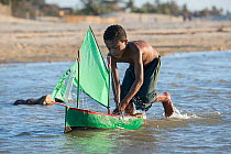 Young Vezo boy, playing with toy boat (pirogue) Morondave, Madagascar. November 2014.