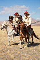 Two eagle hunters mounted on Mongolian horse walks with their female Golden eagles (Aquila chrysaetos) during the Eagle Hunters Festival, near Sagsai, Bayan-Ulgii Aymag, Mongolia. September 2014..