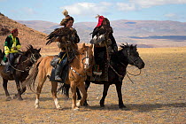 Eagle hunters mounted on their Mongolian horse parade with their female Golden eagles (Aquila chrysaetos) at the Eagle Hunters Festival, near Sagsai, Bayan-Ulgii Aymag, Mongolia. September 2014..