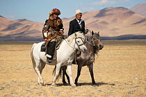 Eagle hunter (left) and Muslim rider walk mounted on their Mongolian horses, at the Eagle Hunters Festival, near Sagsai, Bayan-Ulgii Aymag, Mongolia. September 2014..