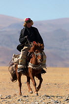 Eagle hunter mounted on Mongolian horse arrives at the Eagle Hunters Festival, near Sagsai, Bayan-Ulgii Aymag, Mongolia. September 2014..