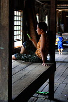 Dayak woman on mobile phone, in longhouse, Pontianka, West Kalimantan, Indonesian Borneo. June 2010.