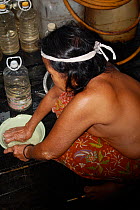 Dayak woman cooking, rehoused by government for dam building project. Sabah, Malaysian Borneo. July 2010.