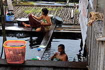 Woman bathing in village in Gunung Palung National Park, Kalimantan, Indonesian Borneo. July 2010.