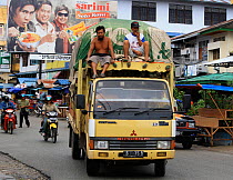 Men riding on the top of truck, Singkawang city, West Kalimantan, Indonesian Borneo. July 2010.