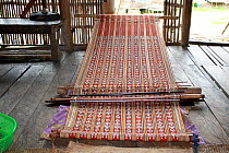 Weaving traditional Iban pua kumbu fabric, in Dayak longhouse, Pontianak, West Kalimantan, Indonesian Borneo. August 2010.