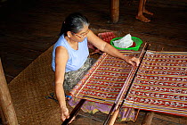 Weaving traditional Iban pua kumbu fabric, in Dayak longhouse, Pontianak, West Kalimantan, Indonesian Borneo. August 2010.