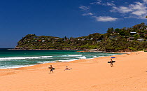 Surfers walking on beach, Australia. November 2012.