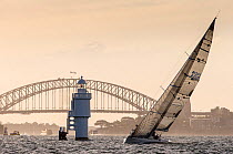 Yacht sailing past a lighthouse in front of the Harbour Bridge in Sydney, New South Wales, Australia, November 2012. All non-editorial uses must be cleared individually.