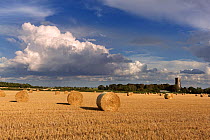 Straw bales and field of stubble, with St James Church, Southrepps, Norfolk, UK August 2014.