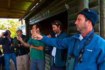 Men holding Eurasian penduline tit (Remiz pendulinus) at bird ringing demonstration, Hula Valley, Israel, November 2014.