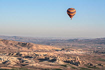 Hot air balloon flying over rock formations, Cappadocia, Turkey, March 2006.