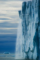 Ice cliff of the Austfonna ice cap with melt water and ice crashing down to the sea, Svalbard, Norway, July 2012.