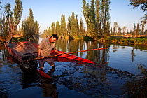 Man extracting mud from the bottom of canal, to be used as fertilizer in a chinampa, a wetland agricultural system. Xochimilco wetlands, Mexico City, December 2011.