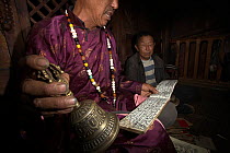 Nakhi shaman performing ceremony and reading from Dongba / Naxi pictographs, Yunnan, China, July 2010.
