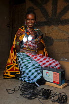 Masai woman with solar powered lights, Masai hut, Mara, Kenya, March 2013.