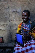 Masai woman with portable television, powered by solar energy,  Masai Mara, Kenya. March 2013.