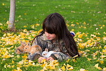Nine-year old girl with mixed-breed rabbit babies; Higganum, Connecticut, USA. Model released.