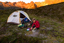 Woman cooking next to tent, Miners Ridge, Glacier Peak Wilderness, Wenatchee National Forest, Washington, USA. Model released.