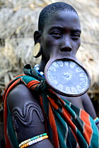 Woman with lip plate, which signifies she is a married woman, she also has traditional scarification on her arm, Mursi tribe, Mago National Park. Ethiopia, November 2014