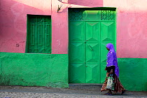 Muslim woman walking down colourful narrow streets, in Harar, an important holy city in the Islamic faith, UNESCO World Heritage Site. Ethiopia, November 2014