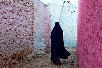 Muslim woman walking down colourful narrow streets, Harar, an important holy city in the Islamic faith, UNESCO World Heritage Site. Ethiopia, November 2014