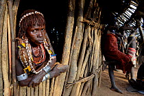 Hamer woman with her traditional clothes and ornaments, looking out of home,  Hamer tribe, Lower Omo Valley. Ethiopia, November 2014