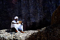 Devout Christian in traditional robes inside courtyard of Northwestern group of churches Lalibela, . UNESCO World Heritage Site. Ethiopia, December 2014.