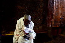 Priest reading Bible in Bet Maryam church (part of the northwestern group of churches in Lalibela). UNESCO World Heritage Site. Lalibela. Ethiopia, December 2014.