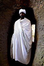 Priest walking through tunnel to Bet Maryam (part of the northwestern group of churches in Lalibela). UNESCO World Heritage Site. Lalibela. Ethiopia, December 2014.