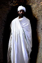 Priest walking through tunnel to Bet Maryam (part of the northwestern group of churches in Lalibela). UNESCO World Heritage Site. Lalibela. Ethiopia, December 2014.