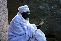Devout Christian in traditional robes studying at Bet Medhane Alem (part of the northwestern group of churches in Lalibela). UNESCO World Heritage Site. Lalibela. Ethiopia, December 2014.