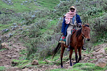 Man on horseback, with towel and cap on head, Bale Mountains National Park. Ethiopia, November 2014