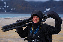 Polar traveler Lisa Widstrand carrying tripod, Svalbard, Norway, Arctic. September 2014.