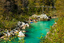 Kayakers on the clear blue waters of the Soca river, Soca Valley, Julian Alps, Slovenia, October 2014.
