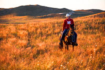 Aaron Price riding his horse 'Beau' over his Ranch, Gracie Creek, Sandhills, Nebraska. Garfield County, Nebraska, USA. October 2014.