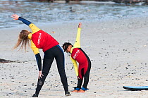 Surfers stretching on beach, Surfers Corner, Muizenberg Beach, False Bay, near Cape Town, Western Cape, South Africa.