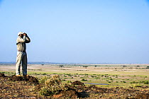 Tortilis Camp guide, Johnathan, looking out from small  hill. Amboseli National Park, Kenya.