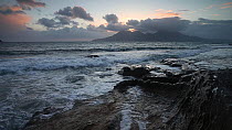 Waves breaking on the shore at sunset, looking towards Rum, Isle of Eigg, Inner Hebrides, Scotland, UK, April 2013.